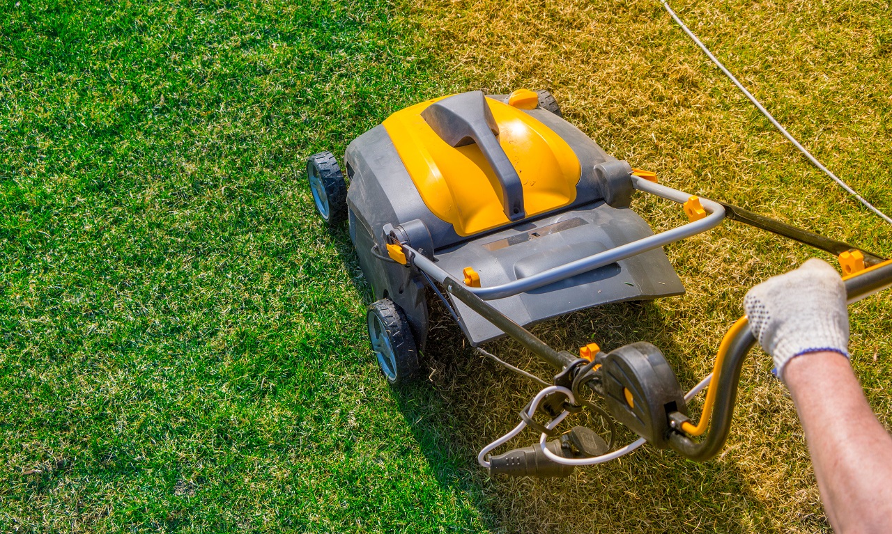 Aeration-of-the-lawn-in-the-garden.-Yellow-aerator-on-green-grass